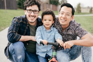 Two dads with toddler son having fun outdoor